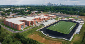 Aerial view during phasing of the new West Charlotte High School overlooking the existing football stadium, while other existing buildings yet to be demolished still in view beyond, Charlotte-Mecklenburg Schools, in Charlotte, NC. Photo: Myles Gelbach
