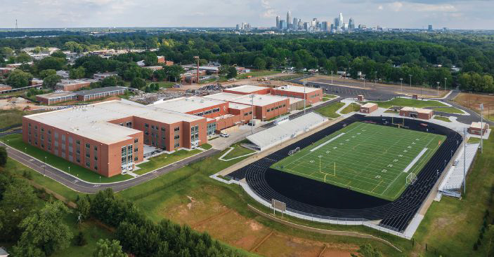 Aerial view during phasing of the new West Charlotte High School overlooking the existing football stadium, while other existing buildings yet to be demolished still in view beyond, Charlotte-Mecklenburg Schools, in Charlotte, NC. Photo: Myles Gelbach